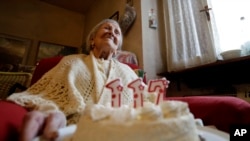 FILE - Emma Morano holds a cake with candles marking 117 years on the day of her birthday, Nov. 29, 2016, in Verbania, Italy. (AP Photo/Antonio Calanni)