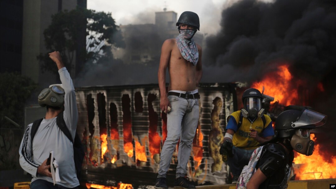 Un camión se quema detrás de los manifestantes durante una protesta en Caracas, el sábado 27 de mayo.