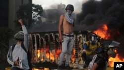 Un camión se quema detrás de los manifestantes durante una protesta en Caracas, el sábado 27 de mayo.