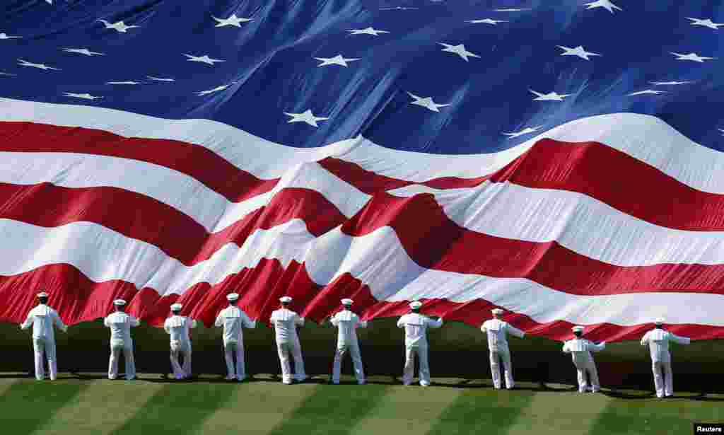 U.S. sailors unravel a huge American flag across the field during opening day ceremonies before the San Diego Padres hosted the Los Angeles Dodgers in their MLB National League baseball game in San Diego, California, Apr. 9, 2013. 