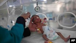 FILE - A medic checks a malnourished newborn baby inside an incubator at Al-Sabeen hospital in Sanaa, Yemen, June 27, 2020. 