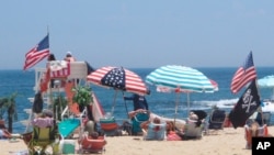 Flags line the beach in Belmar, N.J., as large crowds expected at the Jersey Shore for the July Fourth weekend, some are worried that a failure to heed mask-wearing and social distancing protocols could accelerate the spread of the coronavirus.