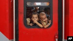 FILE - In this May 30, 2020 photo, Indian migrant worker's children peer out from the window of their train in Prayagraj, India, as they return to villages.