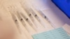 ARCHIVO - Un puñado de jeringuillas listas para ser administrdas vistas en un centro de vacunación de Michigan, EEUU, en abril de 2022.