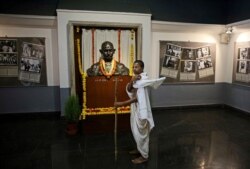 A school boy dressed as Mahatma Gandhi stands next to a bust of Gandhi at Gandhi museum on the eve of his 150th birth anniversary in New Delhi, India, Oct. 1, 2019.