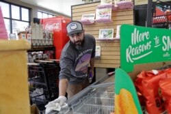 In this photo taken March 20, 2020, Mike Johnston, a clerk at the Maupin Market in Maupin, Oregon, wipes down the ice cream case to protect customers from the coronavirus.