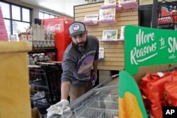 In this photo taken March 20, 2020, Mike Johnston, a clerk at the Maupin Market in Maupin, Oregon, wipes down the ice cream case to protect customers from the coronavirus.