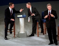 This October 15, 1992 photo shows then President George H. W. Bush, talking with independent candidate Ross Perot as Democratic candidate Bill Clinton stands aside at the end of their second presidential debate in Richmond, Virginia.