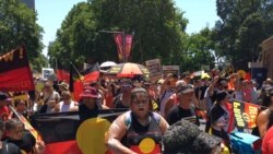 FILE - People carry Australian Aboriginal flags during a demonstration on Australia Day in Sydney, Jan. 26, 2019.