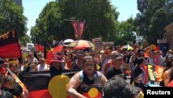 FILE - People carry Australian Aboriginal flags during a demonstration on Australia Day in Sydney, Jan. 26, 2019. 