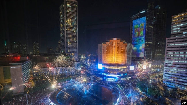 Fuegos artificiales estallan ante la vista de miles de personas congregadas en el principal distrito comercial durante las celebraciones por el Año Nuevo, en Yakarta, Indonesia, el 31 de diciembre de 2024.