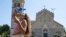 A girl pours a bottle of water on her face and head as she cools off in front of a church in the centre of Messina, on the island of Sicily, during a heat wave on July 16, 2023.