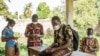 Des agents portant un masque de protection utilisent leur téléphone portable avant une distribution de moustiquaires à Pahou, à 30 km à l'ouest de Cotonou, le 28 avril 2020 avant une distribution de moustiquaires anti-paludisme pendant la pandémie de COVID-19. Pho Yanick Foll/AFP