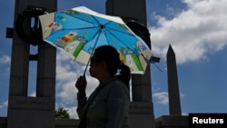Una mujer se protege del sol bajo una sombrilla durante una ola de calor en Washington, EEUU, el 19 de junio de 2024.