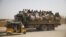 FILE: Migrants sit on their belongings in the back of a truck as it is driven through a dusty road in the desert town of Agadez, Niger, headed for Libya, May 25, 2015. 