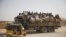 FILE - Migrants sit on their belongings in the back of a truck as it is driven through a dusty road in the desert town of Agadez, Niger, headed for Libya, May 25, 2015. 