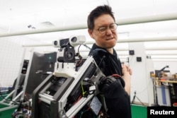 Dennis Hong a professor of Mechanical & Aerospace Engineering at UCLA Samueli School of Engineering attempts to impede the movement of ARTEMIS, a full-sized humanoid robot with first-of-its-kind technology in Los Angeles, California, U.S., April 13, 2023.