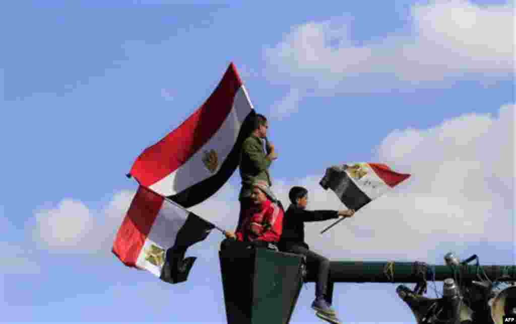 Egyptians protesters wave the national flag from their perch atop a lamp post at a rally to mark the first anniversary of the "Friday of Rage," in Tahrir Square, in Cairo, Egypt, Friday, Jan. 27, 2012. Some 10,000 Egyptian protesters converged on Cairo's 