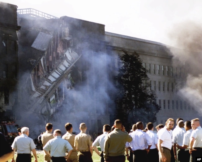 ARCHIVO - Militares y personal del Pentágono observa el martes 11 de septiembre de 2001, el área donde impactó el avión comercial en uno de los laterales de la sede del Departamento de Defensa.