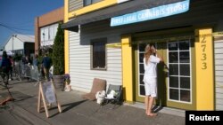 People wait for the "high noon" grand opening at Cannabis City on the first day of legal retail marijuana sales, Seattle, Washington, July 8, 2014.