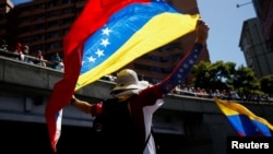 Un partidario de la oposición venezolana sostiene la bandera de Venezuela mientras se reúne con otros partidarios antes de la toma de posesión del presidente Nicolás Maduro para un tercer mandato, en Caracas, Venezuela, el 9 de enero de 2025. REUTERS/Leonardo Fernández Viloria.