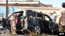 Pasukan keamanan Yaman dan tim penyelamat berkumpul di sekitar bangkai mobil yang terbakar menyusul ledakan yang melanda kota pelabuhan selatan Yaman, Aden, pada 10 Oktober 2021. (Foto: AFP)