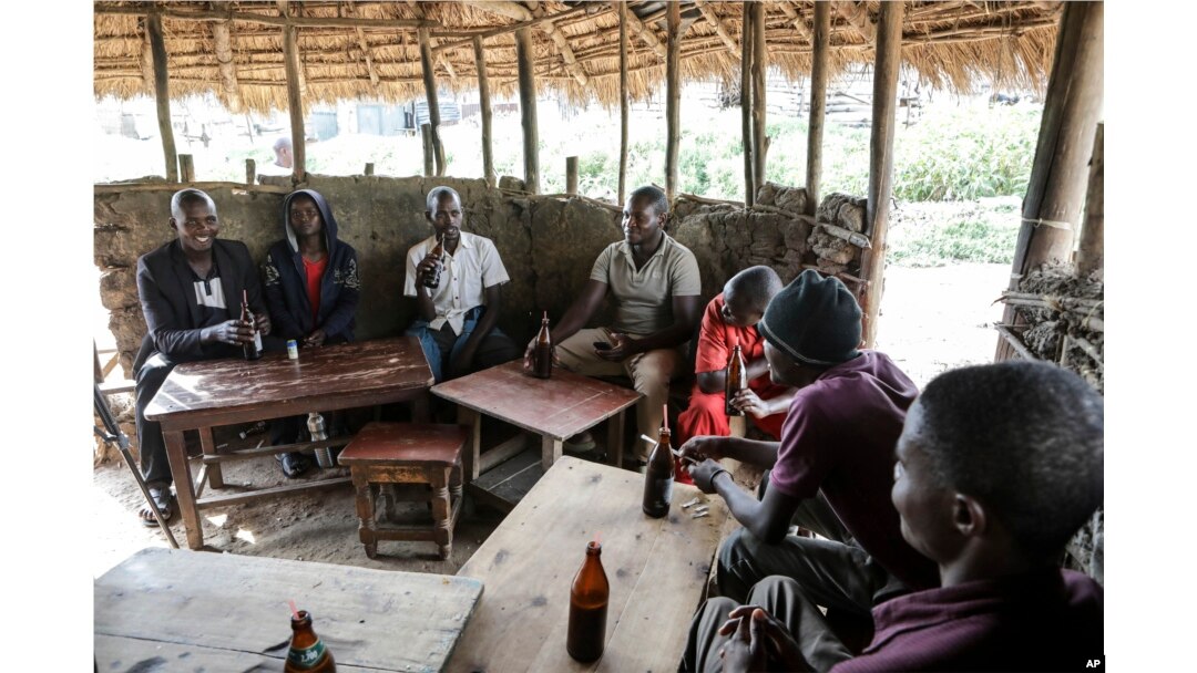 Local patrons share tonto at a local bar in Majengo village, Mbarara, Uganda, on Dec. 10, 2023. The fermented banana juice may become more difficult to find as authorities move to regulate the production of what are considered illicit home brews.