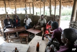 Local patrons share tonto at a local bar in Majengo village, Mbarara, Uganda, on Dec. 10, 2023. The fermented banana juice may become more difficult to find as authorities move to regulate the production of what are considered illicit home brews.