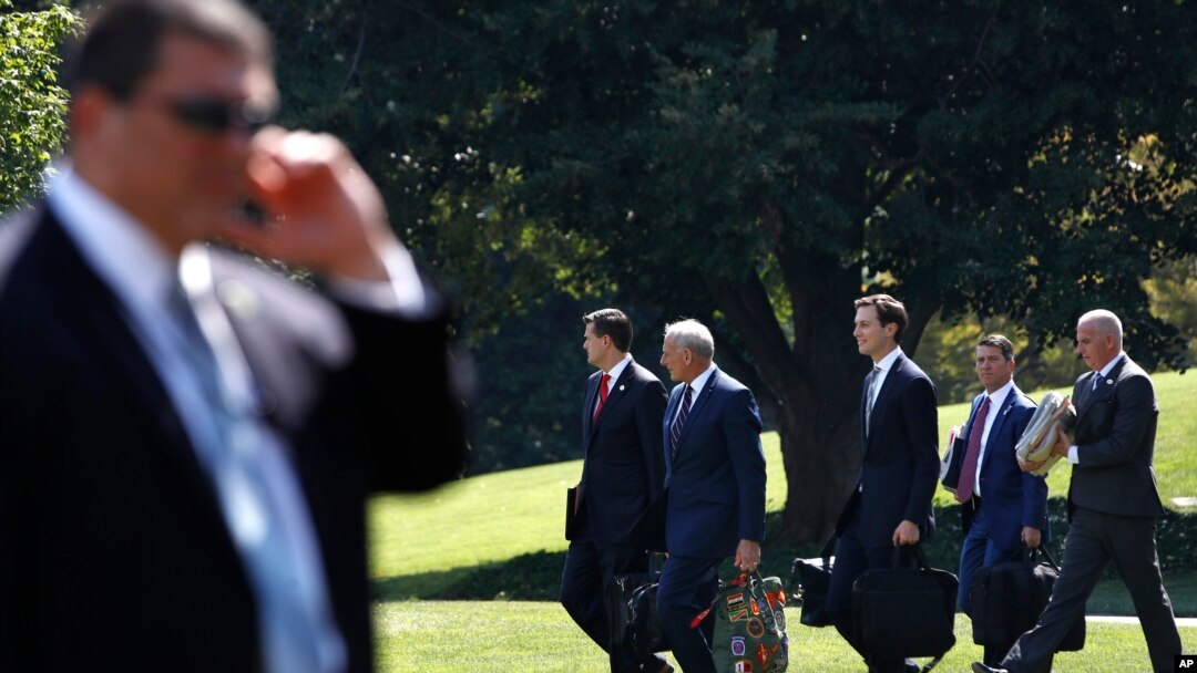 FILE - Members of President Donald Trump's administration walk past a Secret Service agent as they follow Trump to the Marine One helicopter on the South Lawn of the White House in Washington, Aug. 4, 2017. After Trump's controversial remarks on the violence in Charlottesville there is rising speculation that some top officials may be looking for way out.