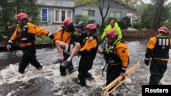 Tim penyelamat membantu evakuasi seorang warga di River Bend, North Carolina yang dilanda badai Florence, Jumat (14.9). 