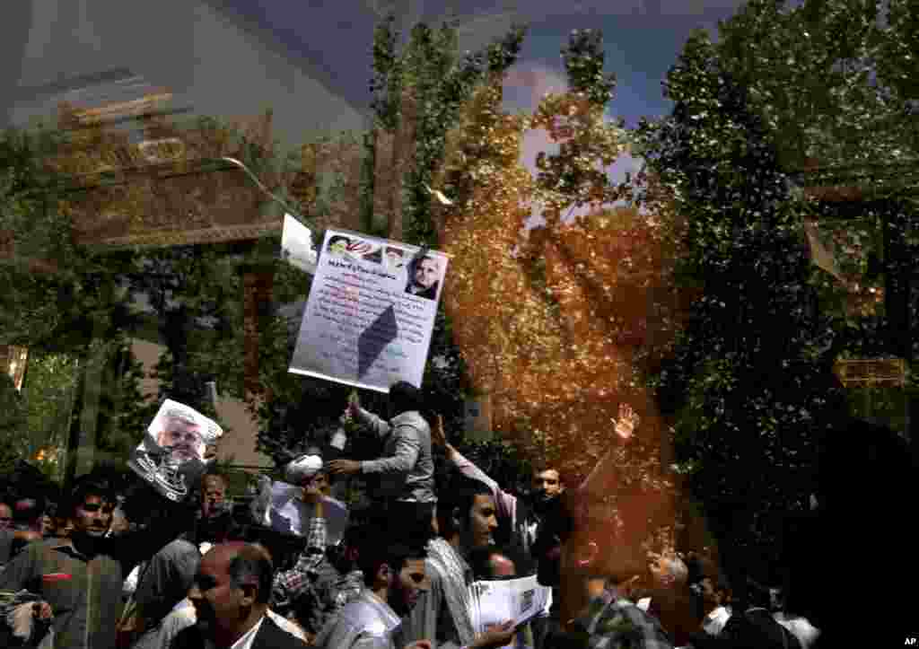 A woman looks out of the window of a public bus as supporters of presidential candidates attend a street campaign, reflected at the window after Friday prayers in Tehran, Iran, June 7, 2013.