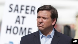 Florida Gov. Ron DeSantis listens during a news conference at a drive-through coronavirus testing site in front of Hard Rock Stadium, March 30, 2020, in Miami Gardens, Fla. 