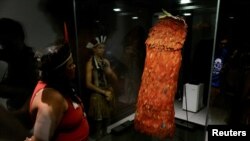 Indigenous people stand next to the Tupinamba cloak, a feathered ceremonial cape used in religious rituals, at the Brazil's National Museum in Rio de Janeiro on Sept. 11, 2024.