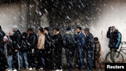 Men wait to buy bread in front of a bakery shop in Syria. (file) 