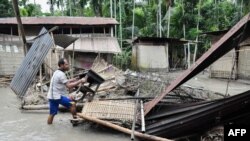 A resident searches for belongings near the debris of a house following flooding in Kasuarbori village, in the northeastern Indian state of Assam, July 13, 2019.