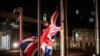 FILE - A worker raises a British flag prior a meeting between European Commission President Ursula von der Leyen and British Prime Minister Boris Johnson at EU headquarters in Brussels, Belgium, Dec. 9, 2020. 