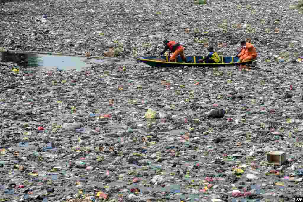 Volunteers and officers from the Great River Basin Management Agency (BBWS) Citarum clean up floating debris trapped by bamboo poles in the Citarum river in Bandung, West Java, Indonesia.