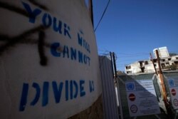 In this photo taken on Nov. 6, 2019, graffiti on a wall reading "Your wall can not divide us" is seen at the U.N buffer zone by a fence that divides the Greek Cypriot south and the Turkish Cypriot north, in divided capital Nicosia, Cyprus.