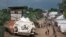In this photo taken Monday, July 25, 2016, some of the more than 30,000 Nuer civilians sheltering in a United Nations base in South Sudan's capital Juba for fear of targeted killings by government forces walk by an armored vehicle and a watchtower manned by Chinese peacekeepers.