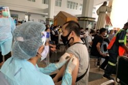 Medical personnel administers the COVID-19 coronavirus vaccine to a man at the Holy Redeemer Catholic church compound in Bangkok on May 9, 2021.