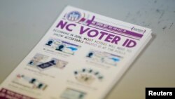 A pile of government pamphlets explaining North Carolina's controversial "Voter ID" law sits on table at a polling station.