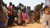 Children queue for food distributed by an NGO in the makeshift camp of Saguia near the capital Niamey, on Sept. 11, 2019, after the Niger river floods forced residents from the area.