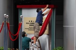 FILE - Workers take off a curtain after attending an opening ceremony for China's new Office for Safeguarding National Security in Hong Kong, July 8, 2020.