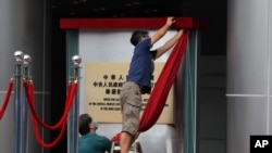 Workers take off a curtain after attend an opening ceremony for China's new Office for Safeguarding National Security in Hong Kong, July 8, 2020.