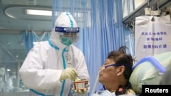 우한 대학병원의 격리 병동에서 보호복을 입은 간호사가 8일 감염 환자에게 음식물을 제공하고 있다.