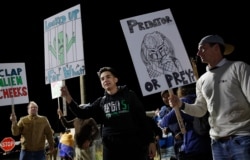 People holds signs at an entrance to the Nevada Test and Training Range near Area 51 near Rachel, Nevada, Sept. 20, 2019.
