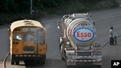 Un autobús público pasa por un camión de distribución de gasolina propiedad de Esso Standard Oil cuando sale de una refinería en Managua, el jueves 6 de diciembre de 2007. 