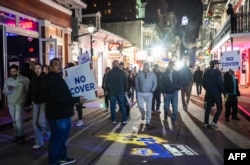 TOPSHOT - Orang-orang berjalan melewati bar-bar di Bourbon Street setelah dibuka kembali untuk umum pada tanggal 2 Januari 2025, di New Orleans, Louisiana, menyusul serangan pada tanggal 1 Januari yang menewaskan 14 orang. (ANDREW CABALLERO-REYNOLDS / AFP)