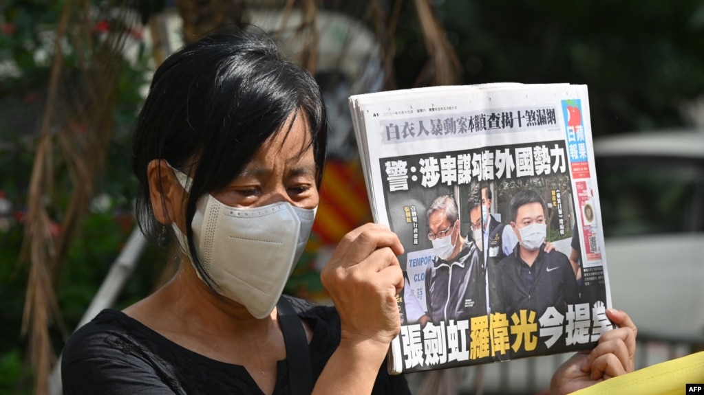 《苹果日报》两名高管——壹传媒行政总裁张剑虹与《苹果日报》总编辑罗伟光——的支持者在香港法庭外的抗议活动中手举《苹果日报》。（2021年6月19日）