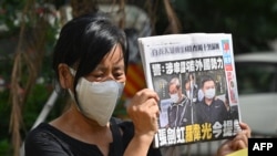 《苹果日报》两名高管——壹传媒行政总裁张剑虹与《苹果日报》总编辑罗伟光——的支持者在香港法庭外的抗议活动中手举《苹果日报》。（2021年6月19日）